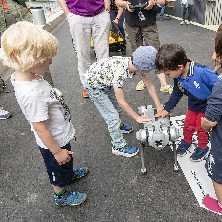 Kinder streicheln einen Roboterhund.