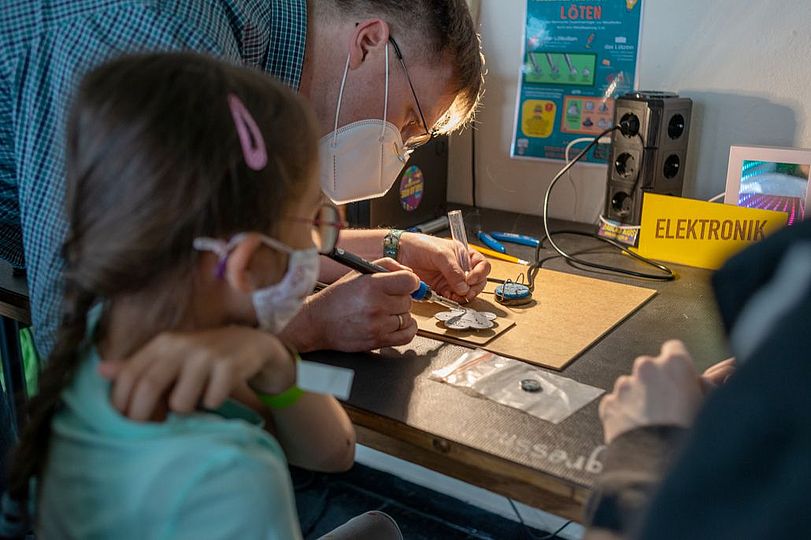 Kiks-Festival: Erwachsener lötet eine Platine.