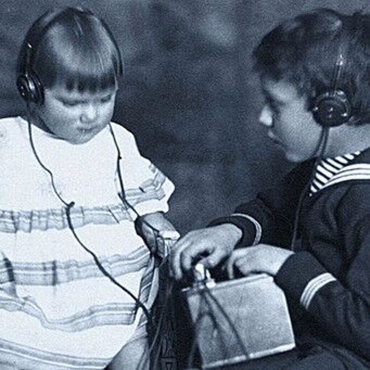 Schwarz-weiß Fotografie zeigt Kinder beim Radioempfang mit Kopfhörern in den 1920er Jahren.