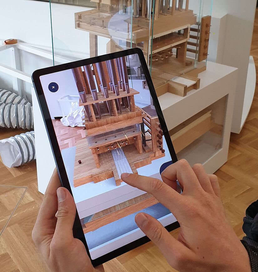 Eine Besucherin steht vor dem Orgelfunktionsmodell in der Musikausstellung und bedient ein Tablet mit dem VR-Modell der Orgel.