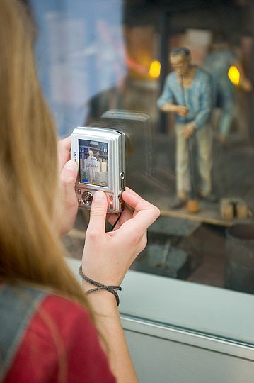 Mädchen fotografiert eine Figur eines Dioramas im Museum.
