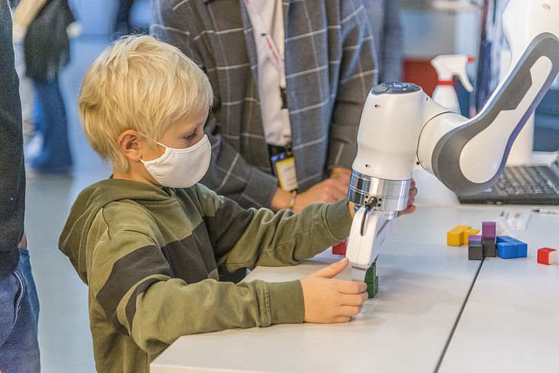 Junge sieht sich Roboterarm an.