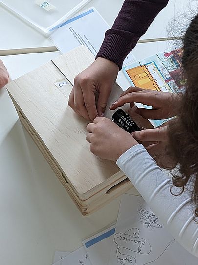 Kinder beim Versuch ein Zahlenschloss zu öffnen.