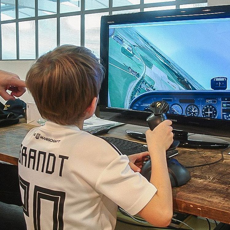 Junge bedient Joystick vor einem Flugsimulaor