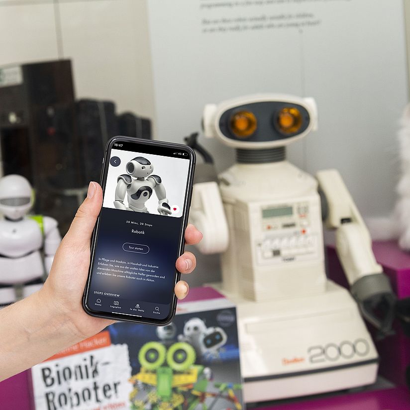 Hand hält Smartphone mit Deutsches Museum App in der Ausstellung Robotik