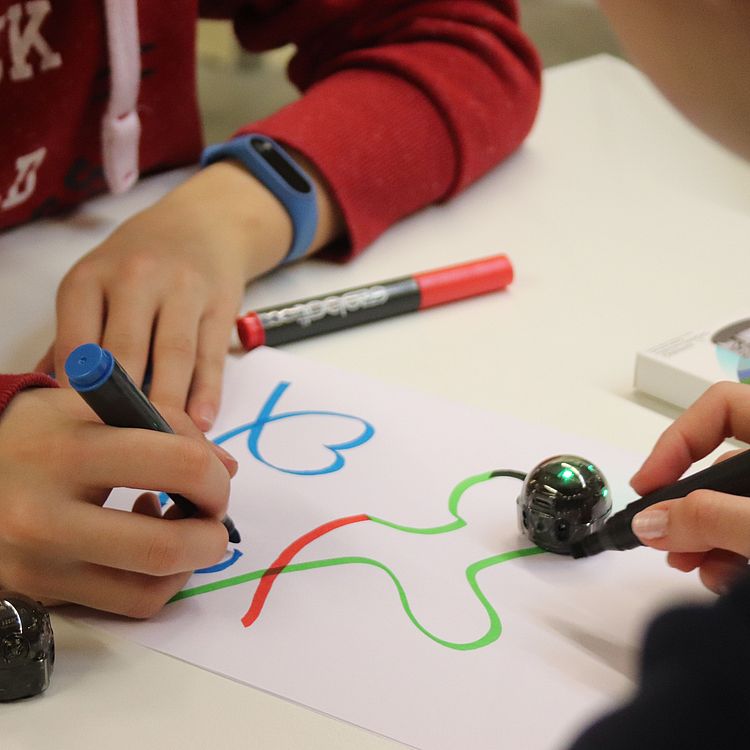 Schulklassenprogramm "Programmieren mit Ozobots" Schüler beim Programmieren von Ozobots auf Papier.