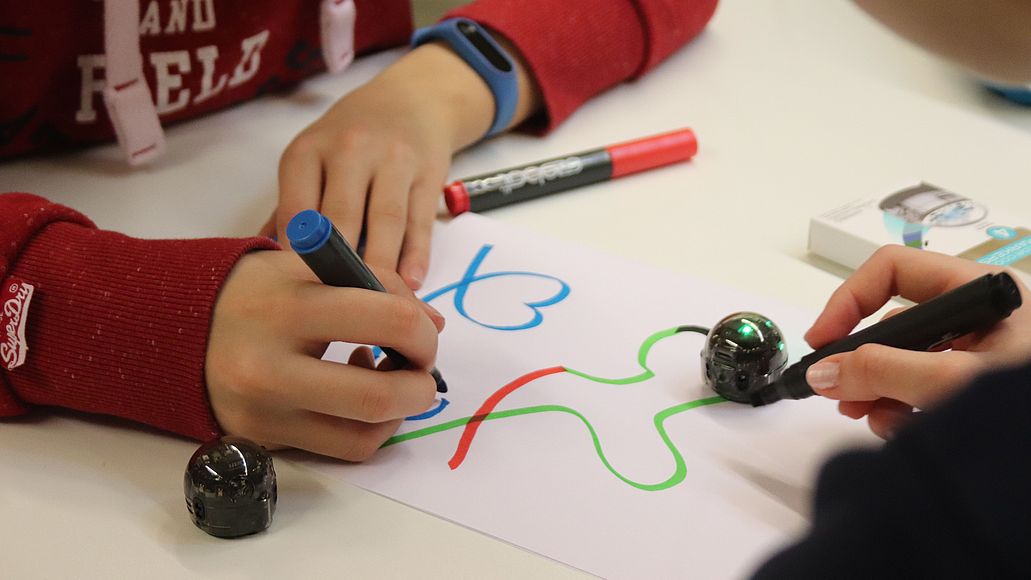 Schulklassenprogramm "Programmieren mit Ozobots" Schüler beim Programmieren von Ozobots auf Papier.
