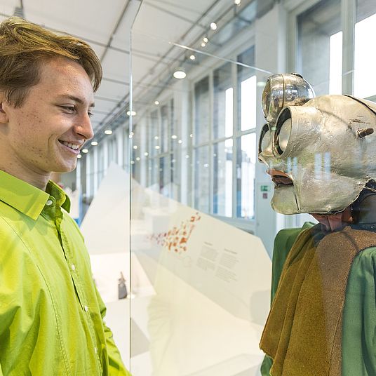 Junger Besucher vor Roboter.