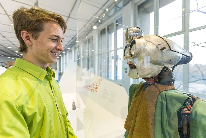 Junger Besucher vor Roboter.