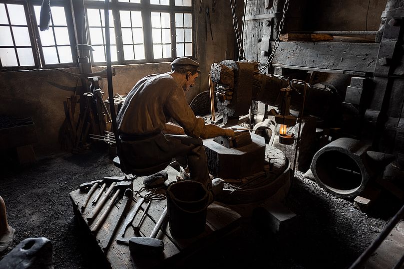 Diorama of a scythe-making forge.