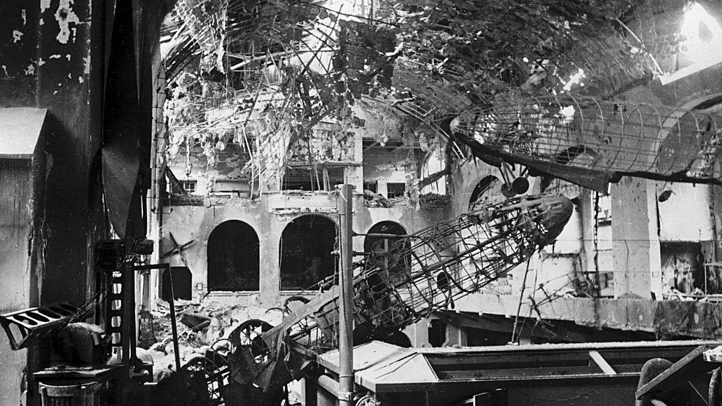 Die Gerippe zweier Zeppeline hängen schräg in der zertrümmerten Luftfahrtabteilung nach Bombentreffern im zweiten Weltkrieg.
