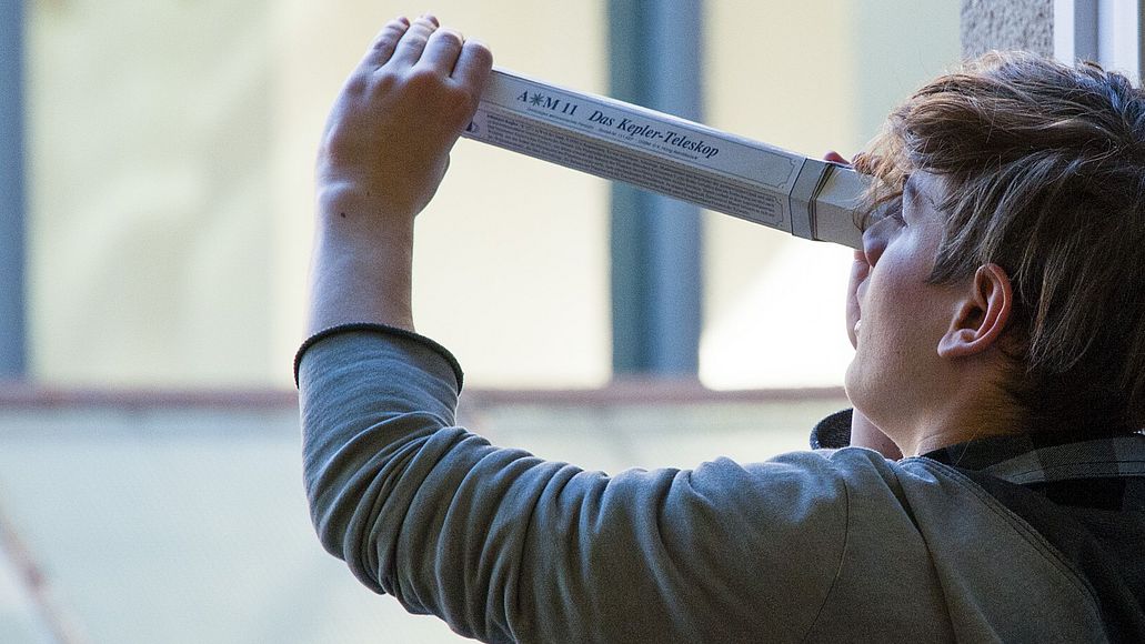 Jugendlicher schaut durch ein selbstgebautes Teleskop.