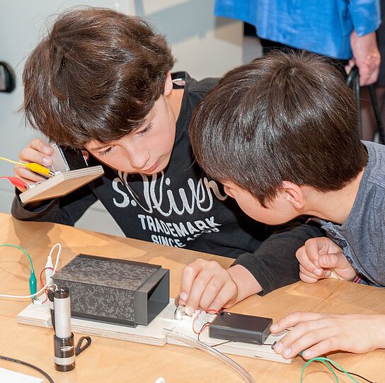Zwei Jungen testen einen selbstgebauten Lautsprecher.