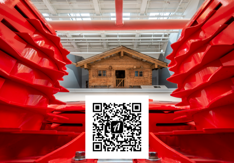 Blick auf die Almhütte in der Ausstellung Landwirtschaft und Ernährung. Am unteren Rand mittig, befindet sich der QR-Code zum Bound "Mit Actionbound in der Landwirtschaft".