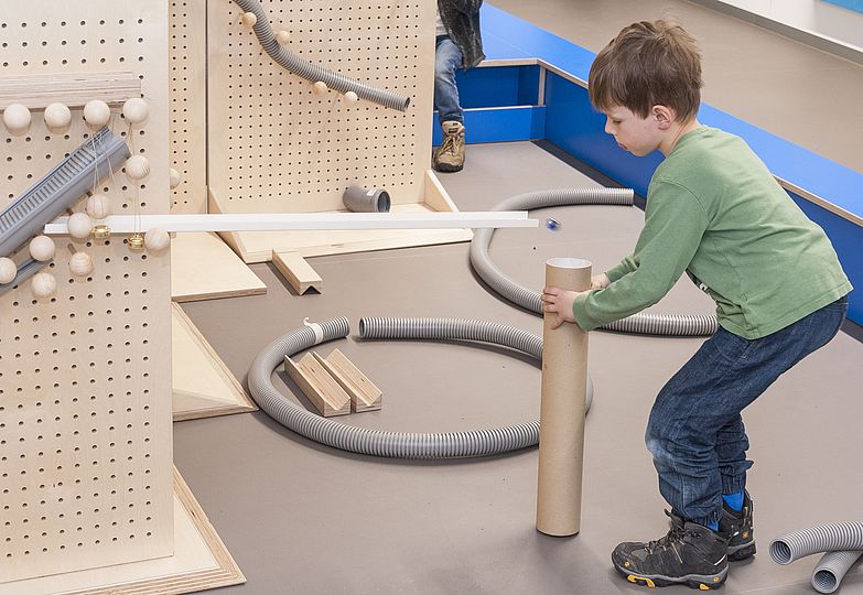 A boy adding to the marble run.