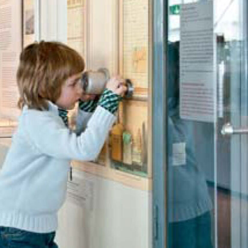 Junge schaut durch ein Guckloch.