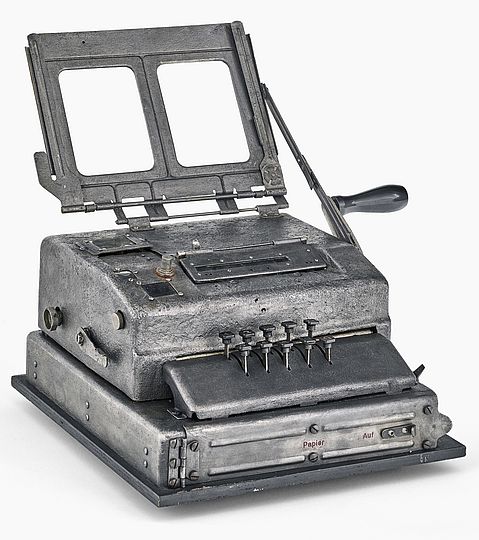 Das Gerät sieht aus wie eine Schreibmaschine und es hat zehn Tasten und eine Kurbel.