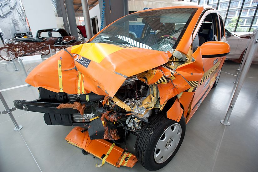 Orangefarbenes Unfallfahrzeug mit eingedrückter Front.