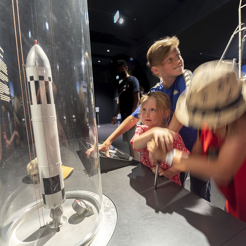 Kinder vor der Mitmachstation "Raketenantrieb" in der Ausstellung Raumfahrt.
