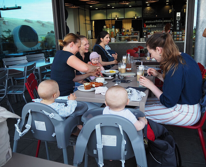 Teilnehmerinnen und Teilnehmer mit ihren Kleinkindern im Dachterassenrestaurant "Frau im Mond".