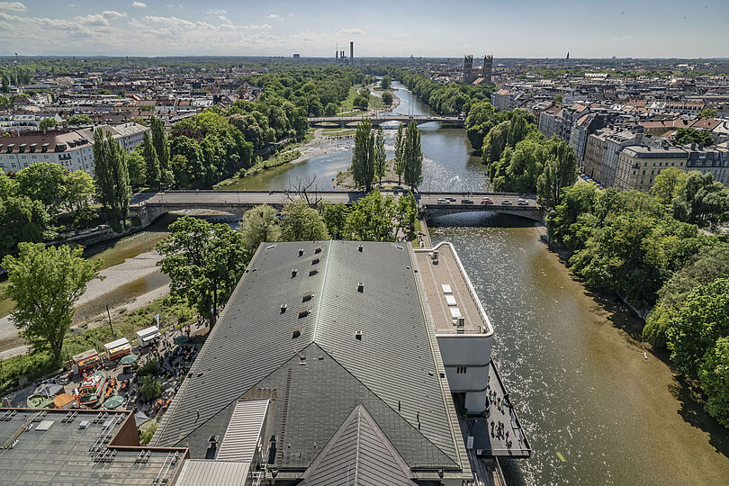 Das Dach des Eingangsgebäudes und die Isar, am Ufer mit Bäumen begrünt von der Aussichtsplattform des Turms gesehen.