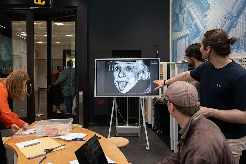 Menschen diskutieren vor Einsteinplakat