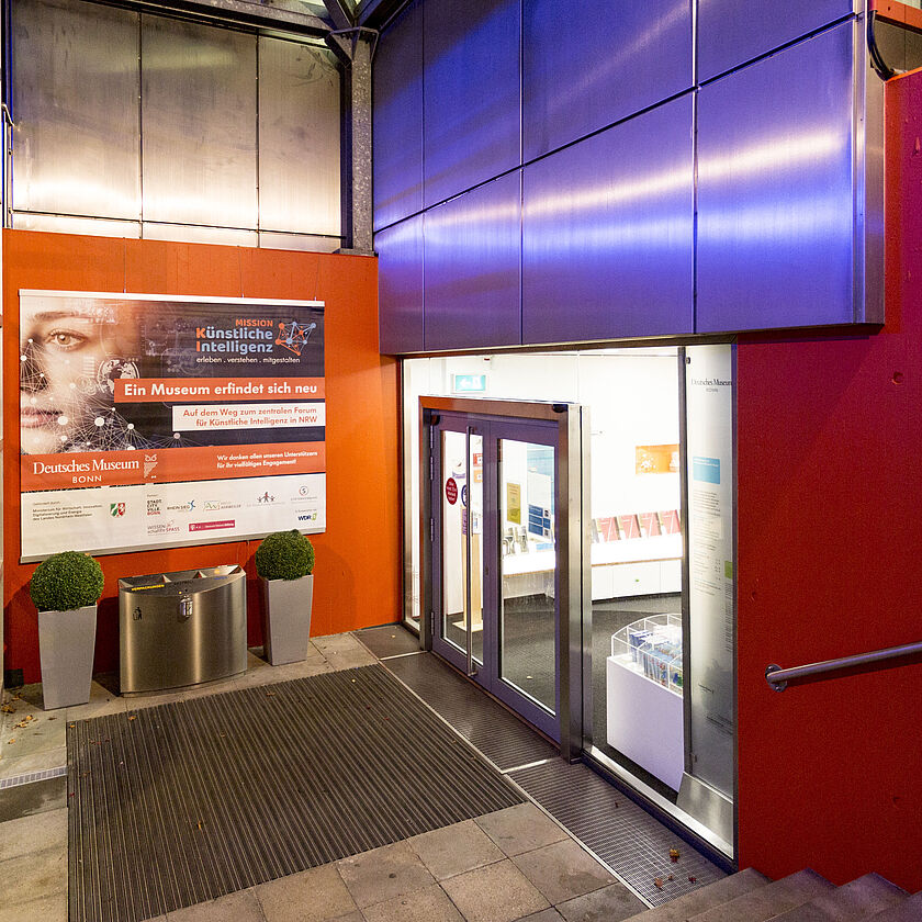Eingang Deutsches Museum Bonn abends mit Banner neu Mission KI und Außenlift