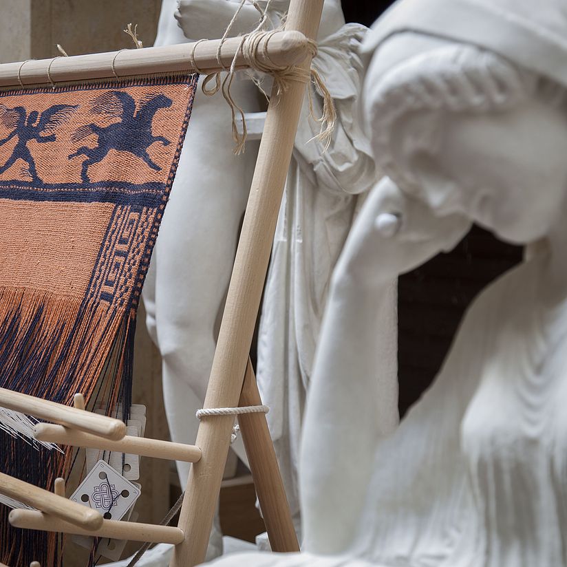 Warp-weighted loom with reconstruction of a fabric with reconstructed Penelope sculpture in the front