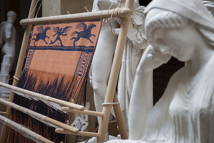 Warp-weighted loom with reconstruction of a fabric with reconstructed Penelope sculpture in the front