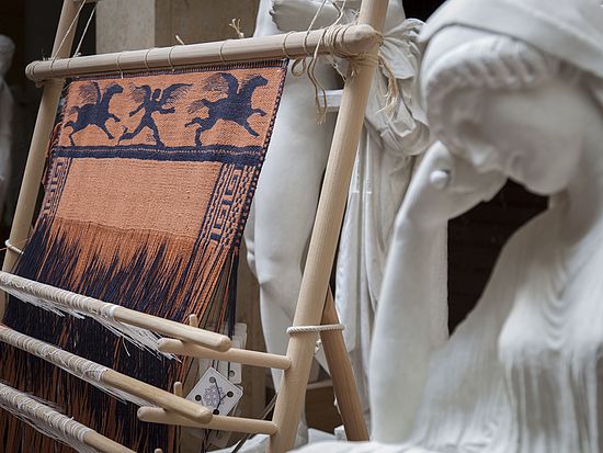 Gewichtswebstuhl mit Rekonstruktion eines Gewebes; davor die rekonstruierte Figur der Penelope.