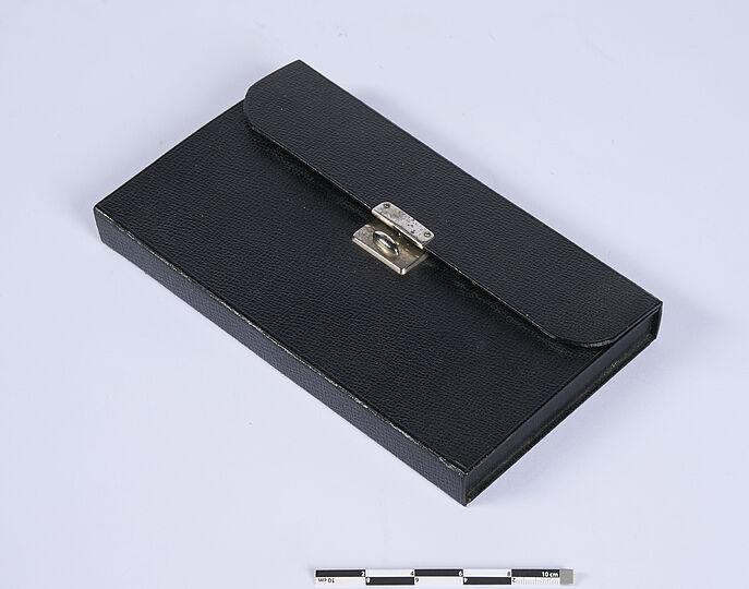 Geschlossenes schwarzes Leder-Etui mit silberner Schnalle.