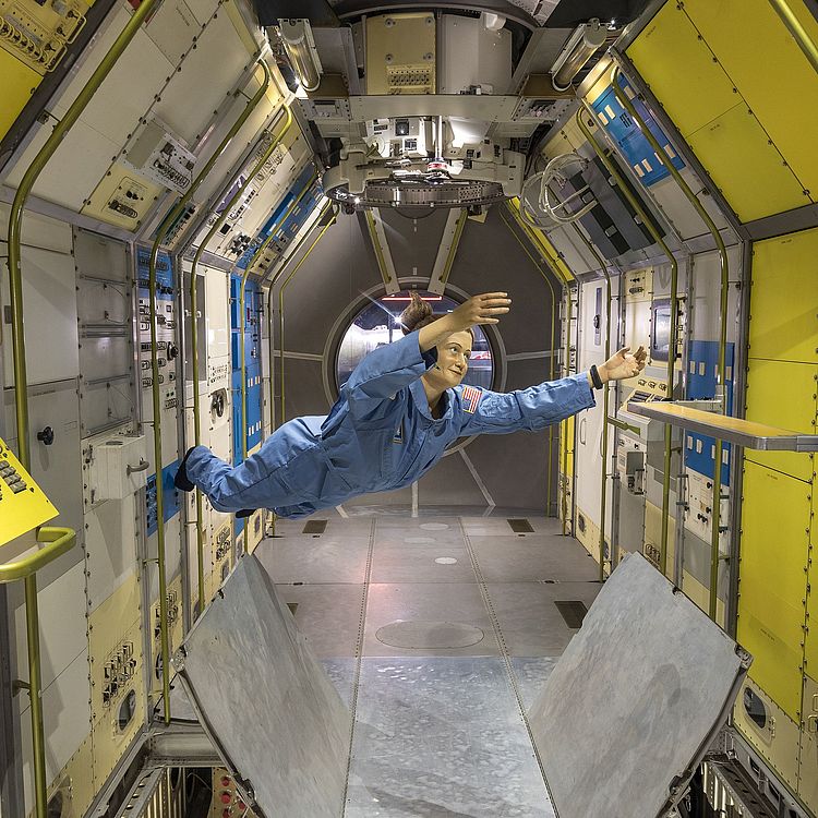 Lebensgroße Figur einer Astronautin schwebt im Weltraumlabor Spacelab.