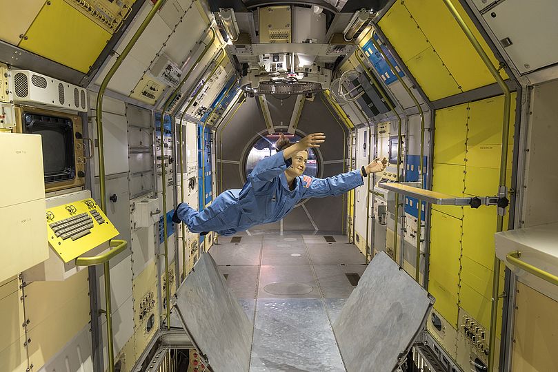 Lebensgroße Figur einer Astronautin schwebt im Weltraumlabor Spacelab.