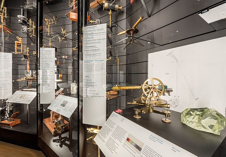 Blick in die Schatzkammer optischer Instrumente in der Ausstellung Klassische Optik. Rechts in der Vitrine ist unter anderem der Prismenspektalapparat von Joseph von Fraunhofer zu sehen.