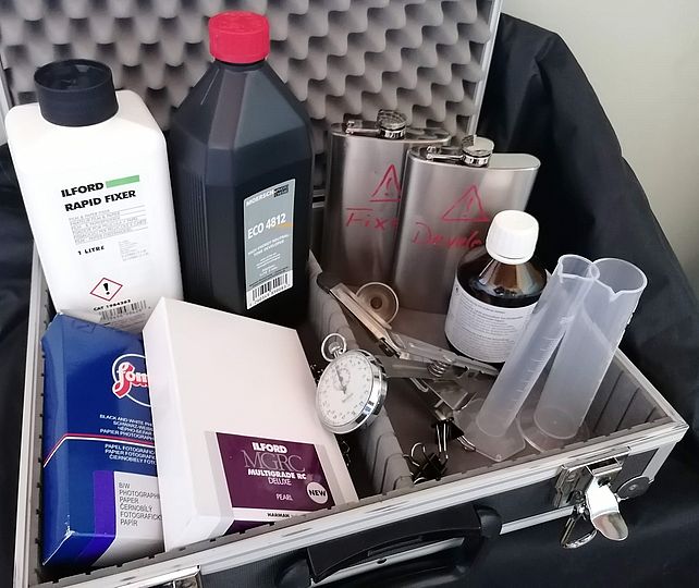 Ein Koffer voll mit Zutaten die man für die analoge Fotoentwicklung benötigt.