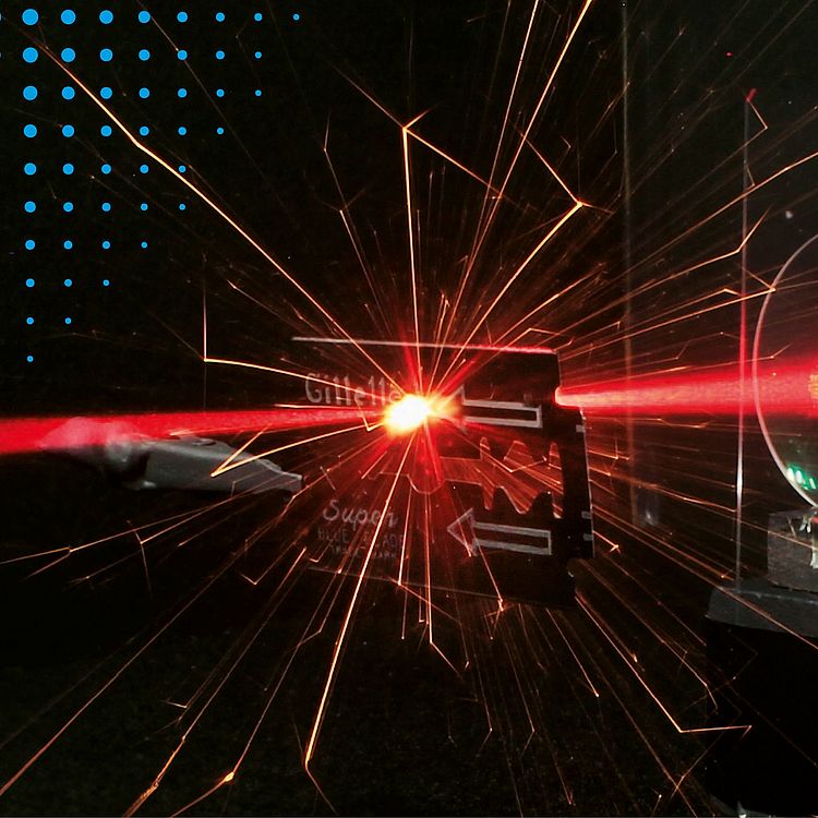 Laser trifft auf Rasierklinge und erzeugt Lichtfunken.