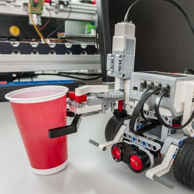 Greifer-Roboter EV3 hält einen roten Plastikbecher.