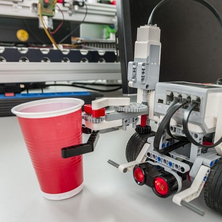 Greifer-Roboter EV3 hält einen roten Plastikbecher.