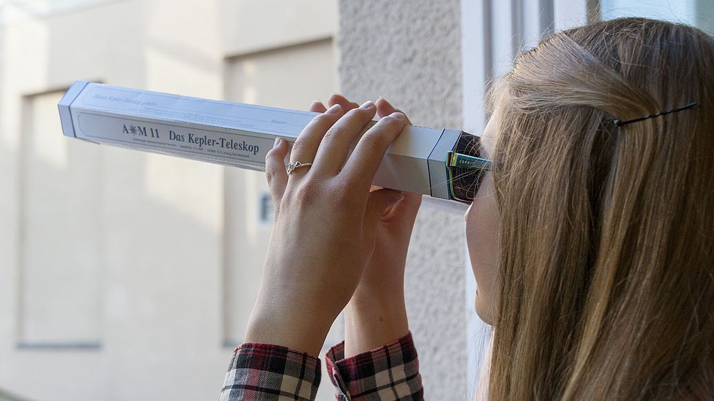 Jugendliche schaut durch ein selbstgebautes Teleskop.