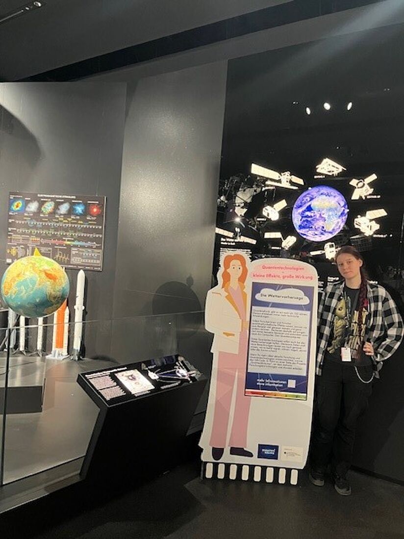 Frau neben Ausstellungsplakat