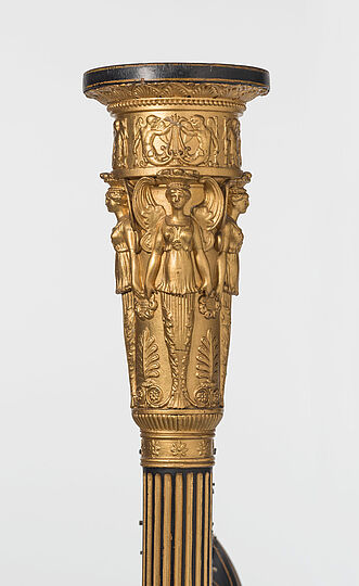 Frontalansicht des Harfenkopfs mit Figuren und dekorativen Ornamenten.