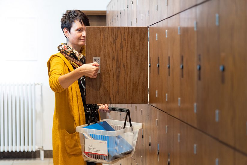Eine Besucherin öffnet ein Schließfach in der Garderobe in der Eingangshalle.