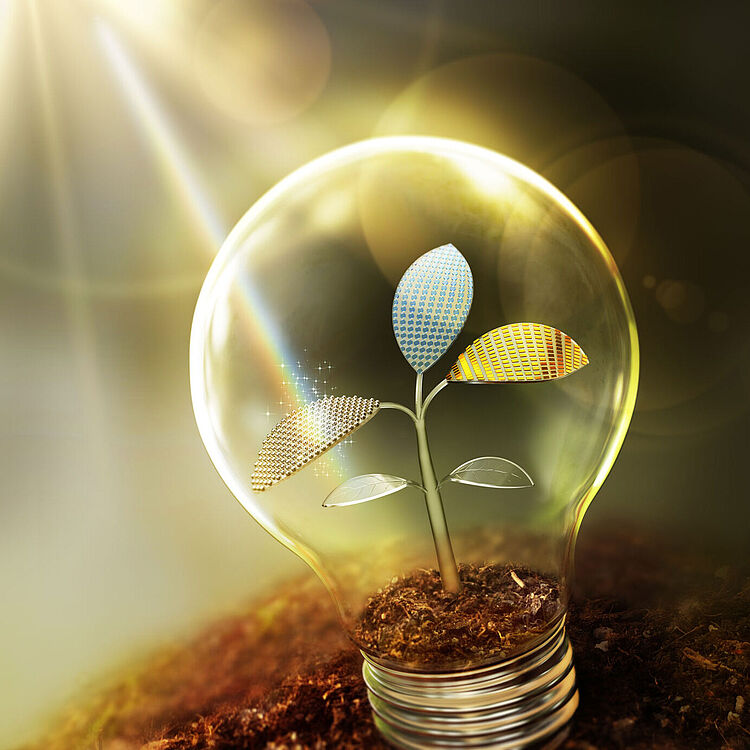 Glühbirne steht auf Erde, in ihrem Inneren ein zarter Pflanzenstängel mit vier Blättern, zwei oben metallisch mit Solarzellenmuster und gold-blau reflektierend, Sonnenstrahlen fallen von oben links und erzeugen Lensflares und warme Lichtstimmung.