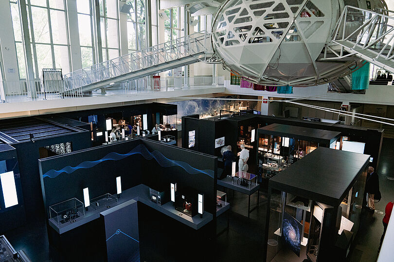 Schwarze Vitrinen mit Exponaten aus Licht und Materie im Untergeschoss des Auditoriums. 
